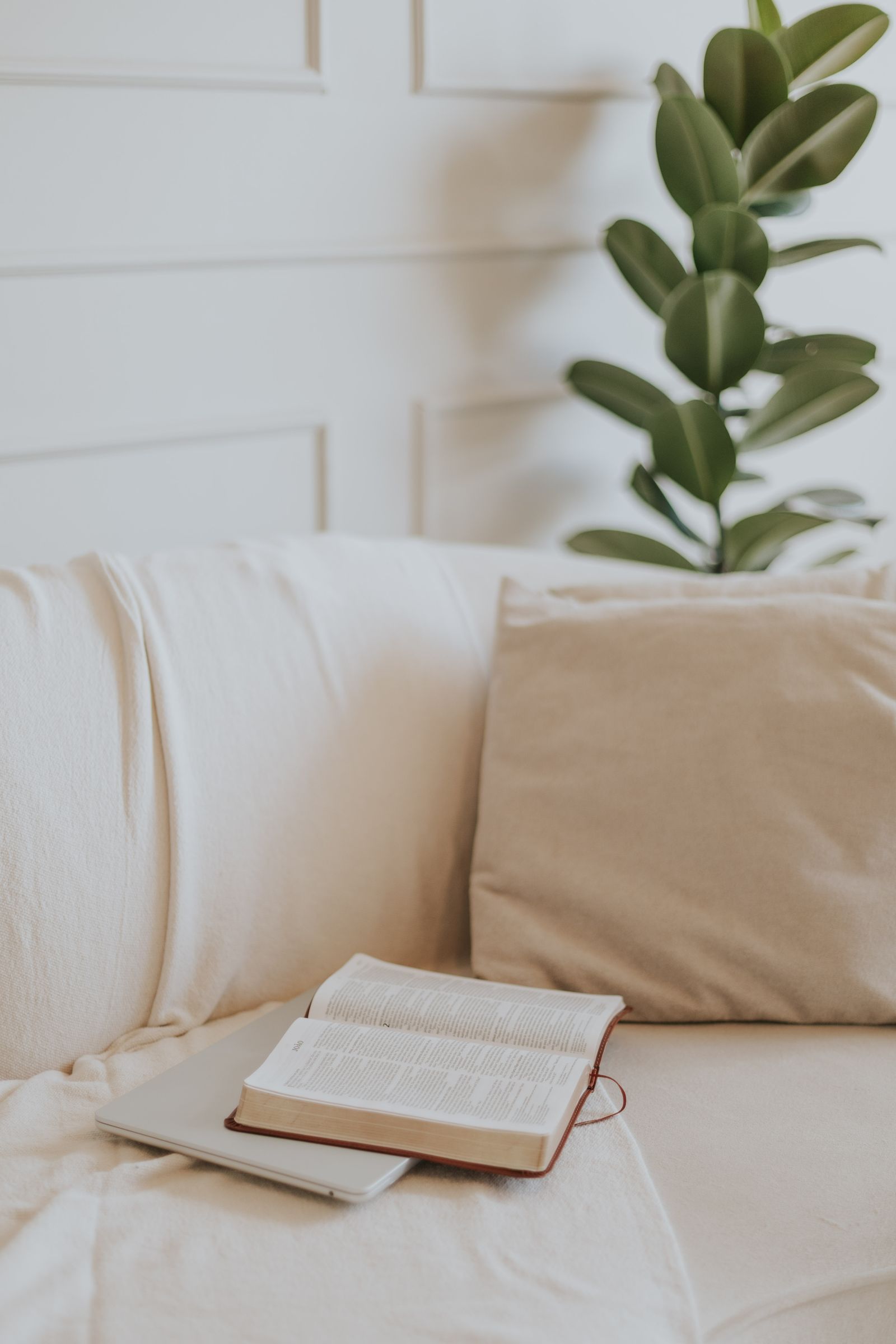 A quiet prayer corner at home with a linen armchair, an open Bible, a candle and a journal in warm morning light