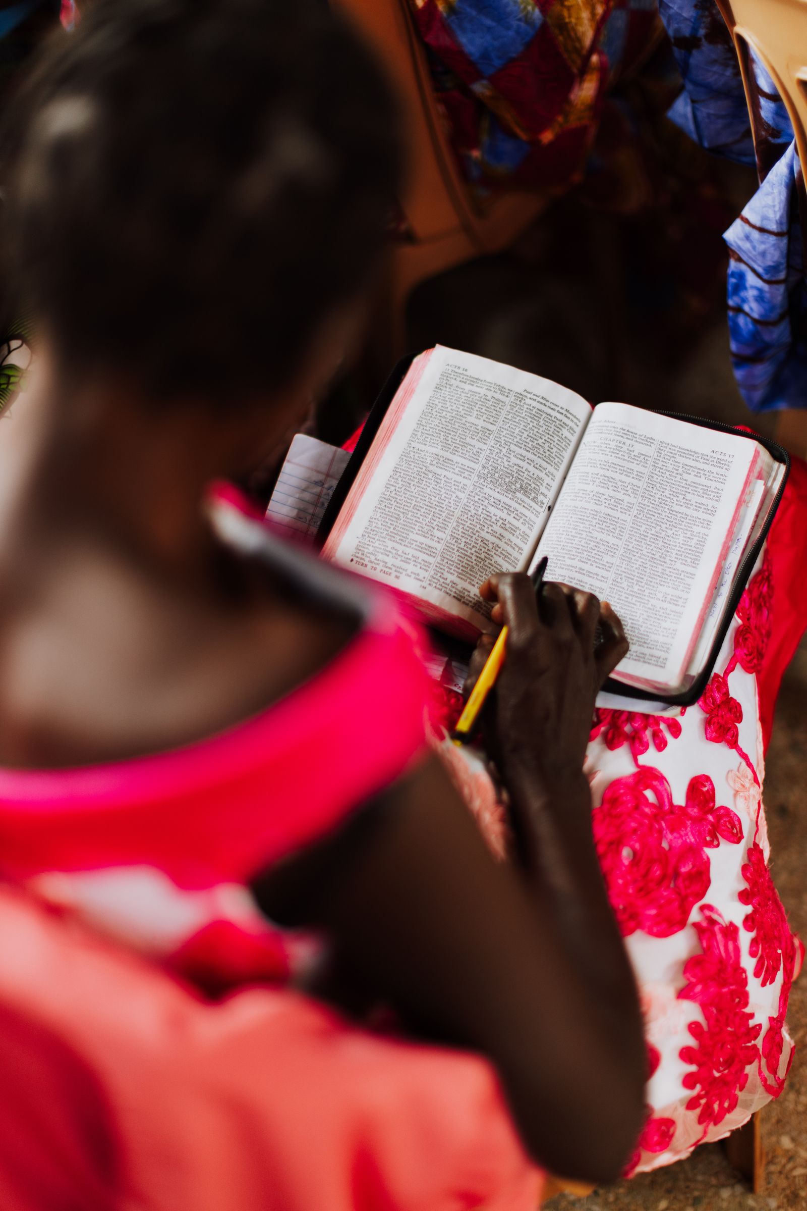 Hand copying a Bible verse into a lined journal with colored pens