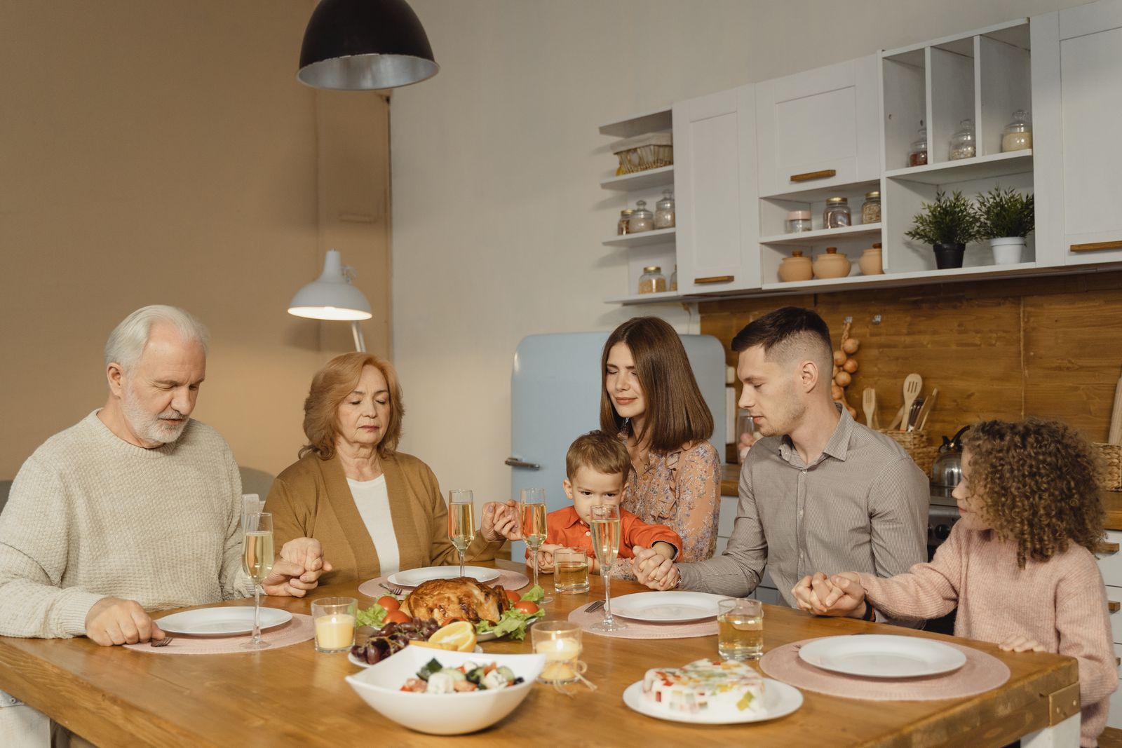 A family gathered around the dinner table with heads bowed in prayer