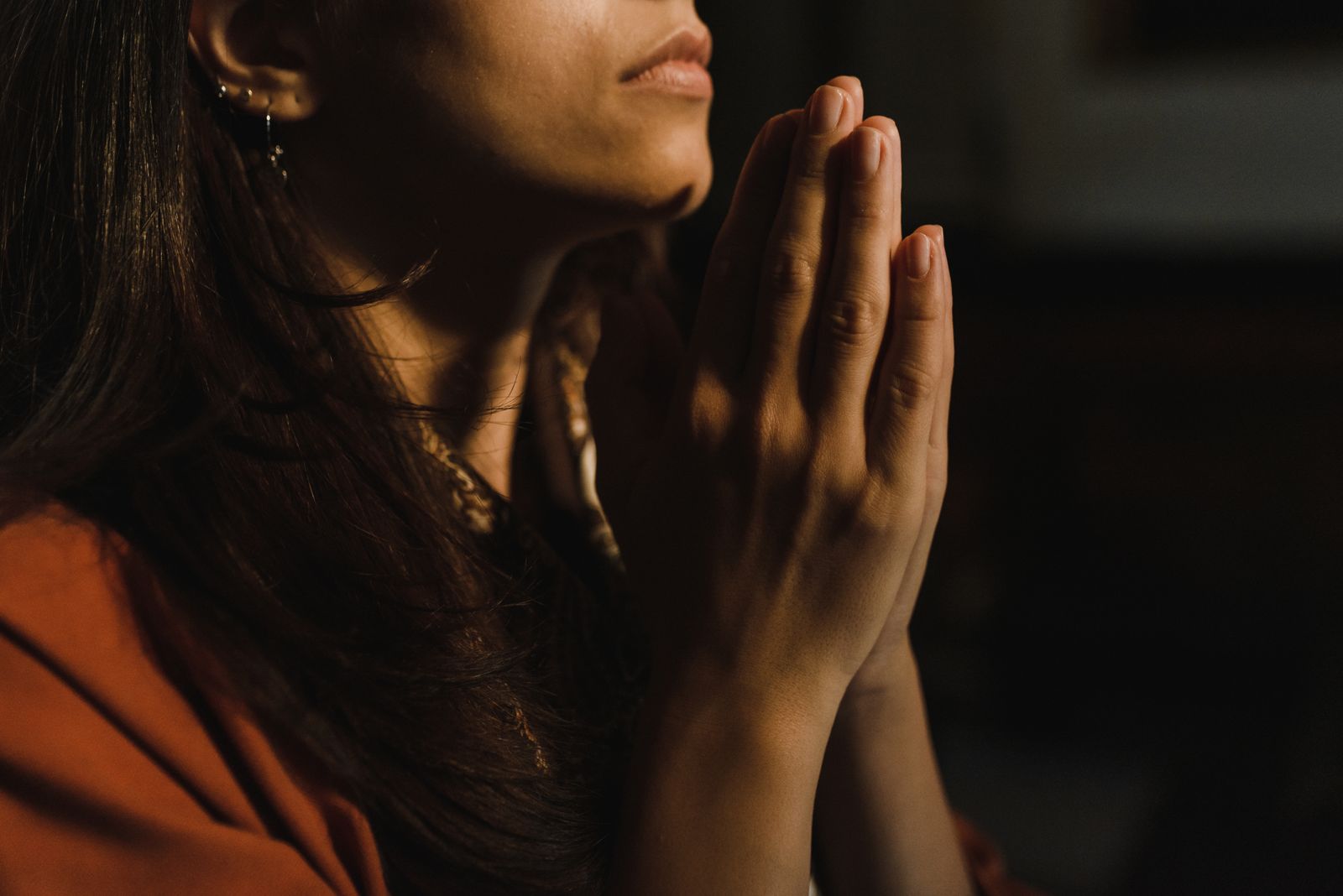 A woman in prayer, hands folded in warm light