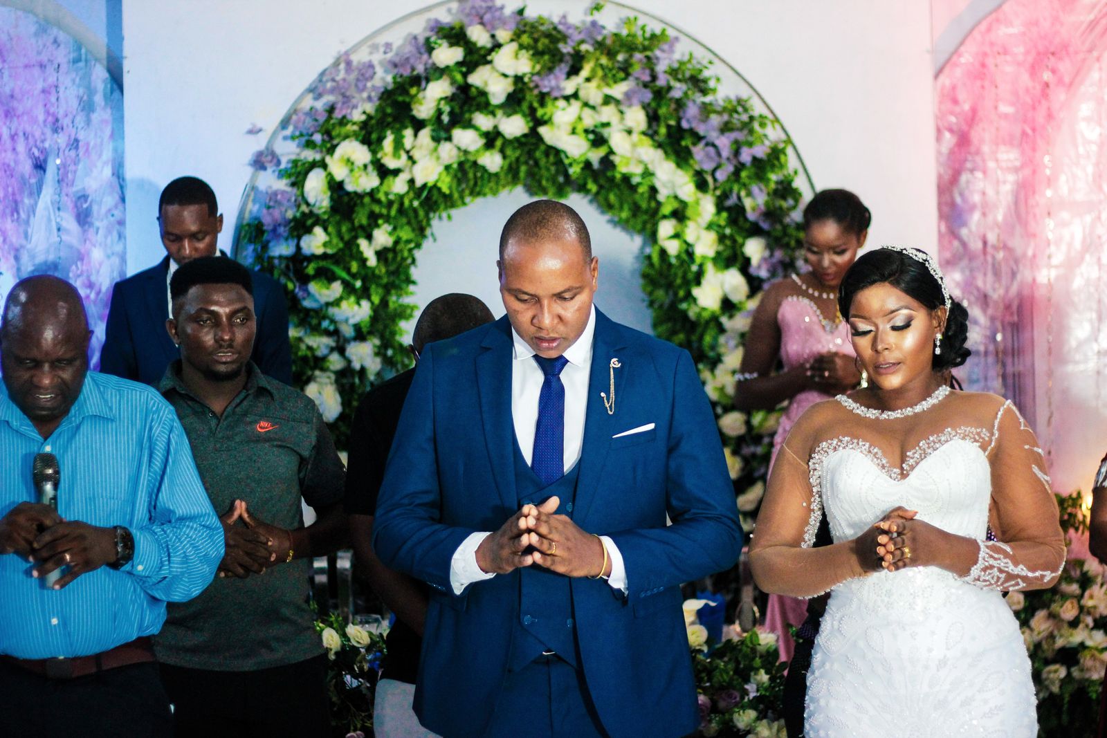 A married couple holding hands in prayer beside a closed Bible